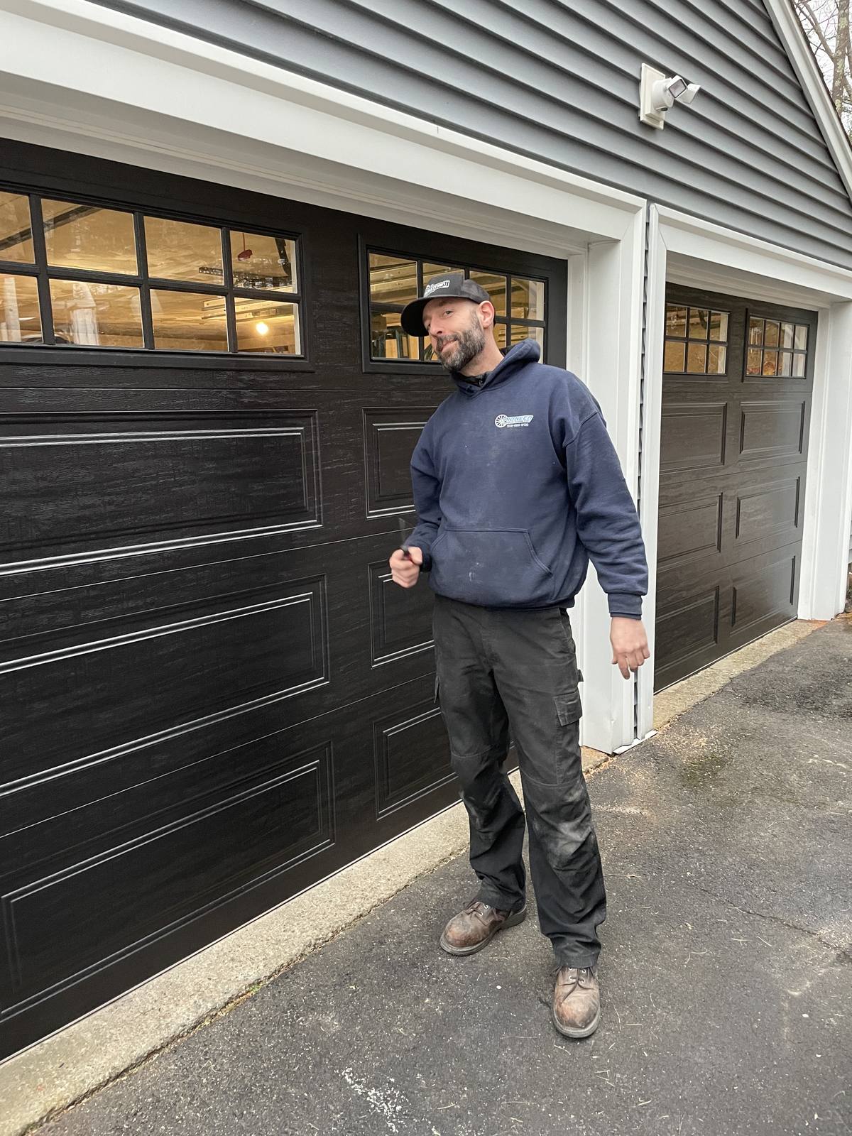 A Pioneer Garage Door technician on a service call at a home with two black garage doors